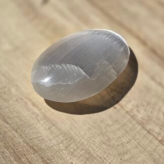 Galet de sélénite blanche de 7 cm utilisé pour la purification énergétique, la méditation et l’harmonisation des lieux.