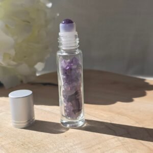 Roll-on en améthyste poli rempli d’huile essentielle, posé sur une surface naturelle