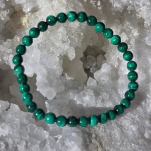 Bracelet en perles naturelles de malachite claire 6 mm posé délicatement sur une géode de quartz