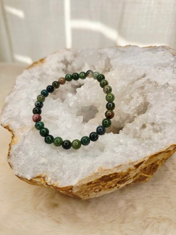 Bracelet en agate indienne naturelle de 6 mm, posé sur une géode de quartz blanc.