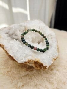 Bracelet en agate indienne naturelle de 6 mm, posé sur une géode de quartz blanc.