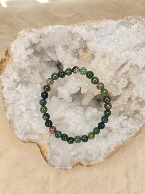 Bracelet en agate indienne naturelle de 6 mm, posé sur une géode de quartz blanc.