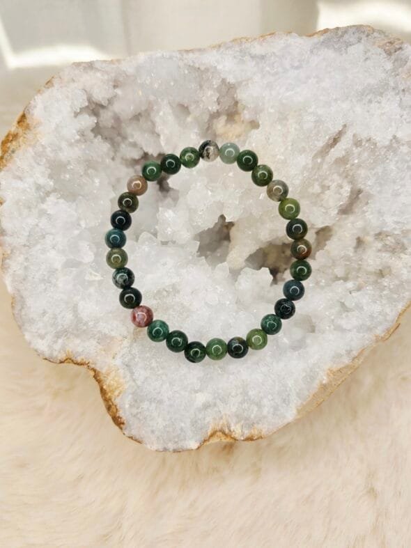 Bracelet en agate indienne naturelle de 6 mm, posé sur une géode de quartz blanc.