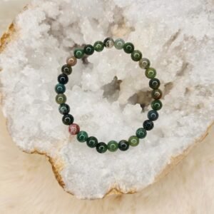 Bracelet en agate indienne naturelle de 6 mm, posé sur une géode de quartz blanc.