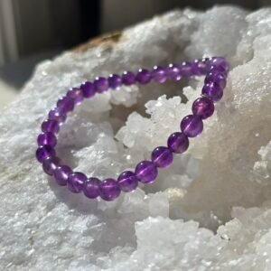 Bracelet en améthyste naturelle 6 mm posé sur une géode de quartz