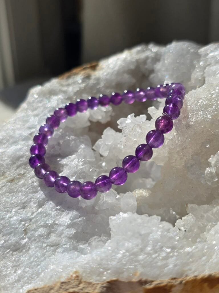 Bracelet en améthyste naturelle 6 mm posé sur une géode de quartz