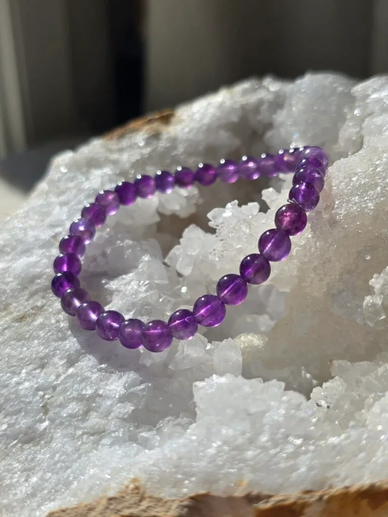 Bracelet en améthyste naturelle 6 mm posé sur une géode de quartz