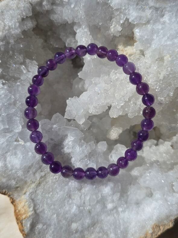 Bracelet en améthyste naturelle 6 mm posé sur une géode de quartz