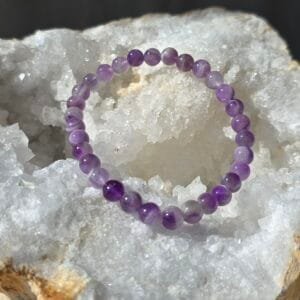 Bracelet en améthyste chevron naturelle 6 mm posé sur une géode de quartz