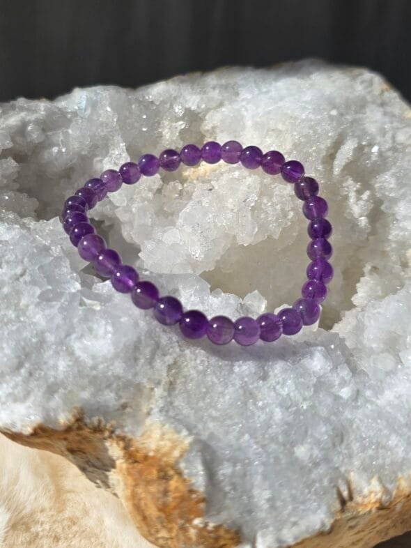 Bracelet en améthyste naturelle 6 mm posé sur une géode de quartz