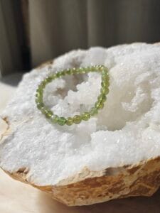 Bracelet en apatite verte naturelle 6 mm posé sur une géode de quartz