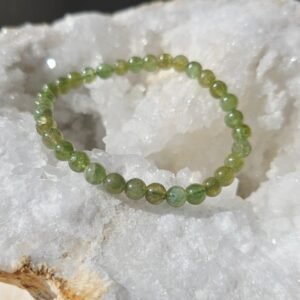 Bracelet en apatite verte naturelle 6 mm posé sur une géode de quartz