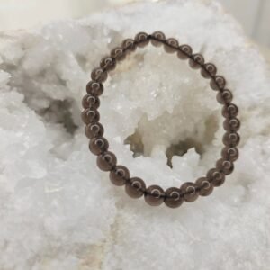 Bracelet en perles naturelles d’obsidienne Larme d’Apache 6 mm posé sur géode quartz