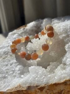 Bracelet en perles naturelles de pierre de lune 8 mm posé sur une géode de quartz blanc.