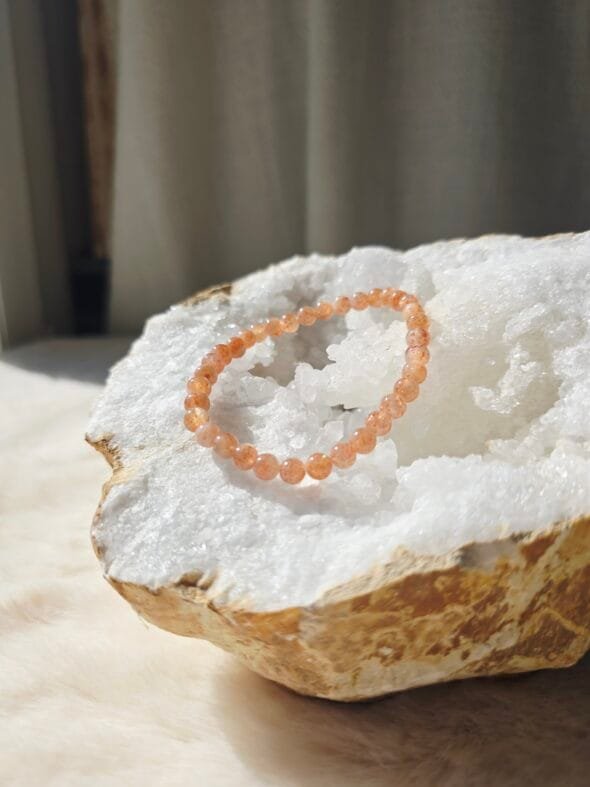 Bracelet en perles naturelles de pierre de soleil 6 mm posé sur une géode