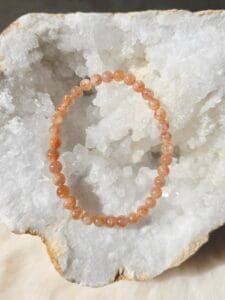 Bracelet en perles naturelles de pierre de soleil 6 mm posé sur une géode