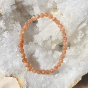 Bracelet en perles naturelles de pierre de soleil 6 mm posé sur une géode