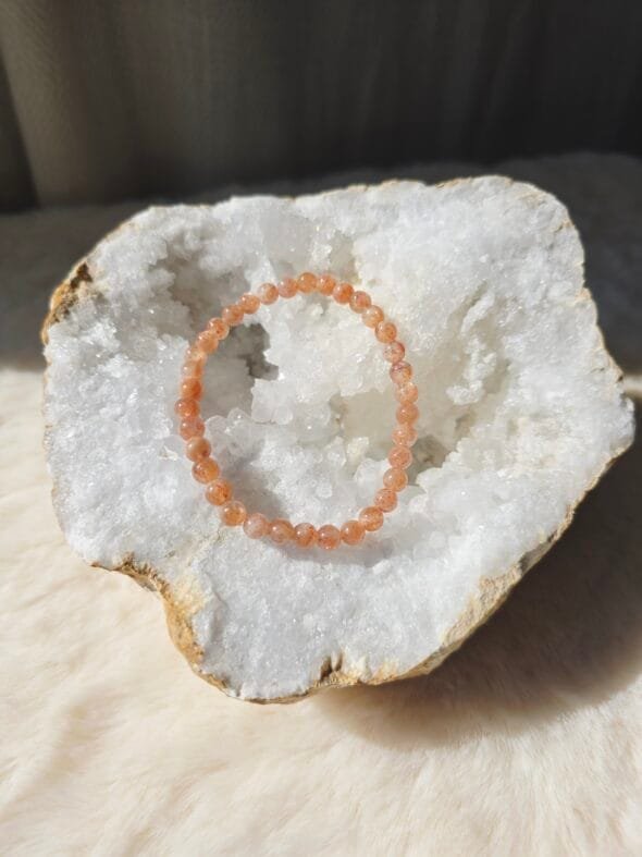 Bracelet en perles naturelles de pierre de soleil 6 mm posé sur une géode