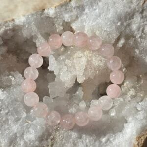 Bracelet en quartz rose naturel 10 mm posé sur une géode de quartz