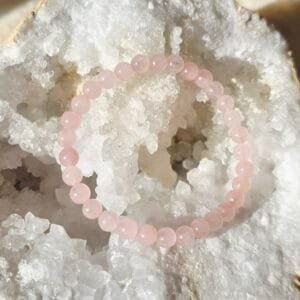 Bracelet en quartz rose naturel 6 mm posé sur une géode de quartz