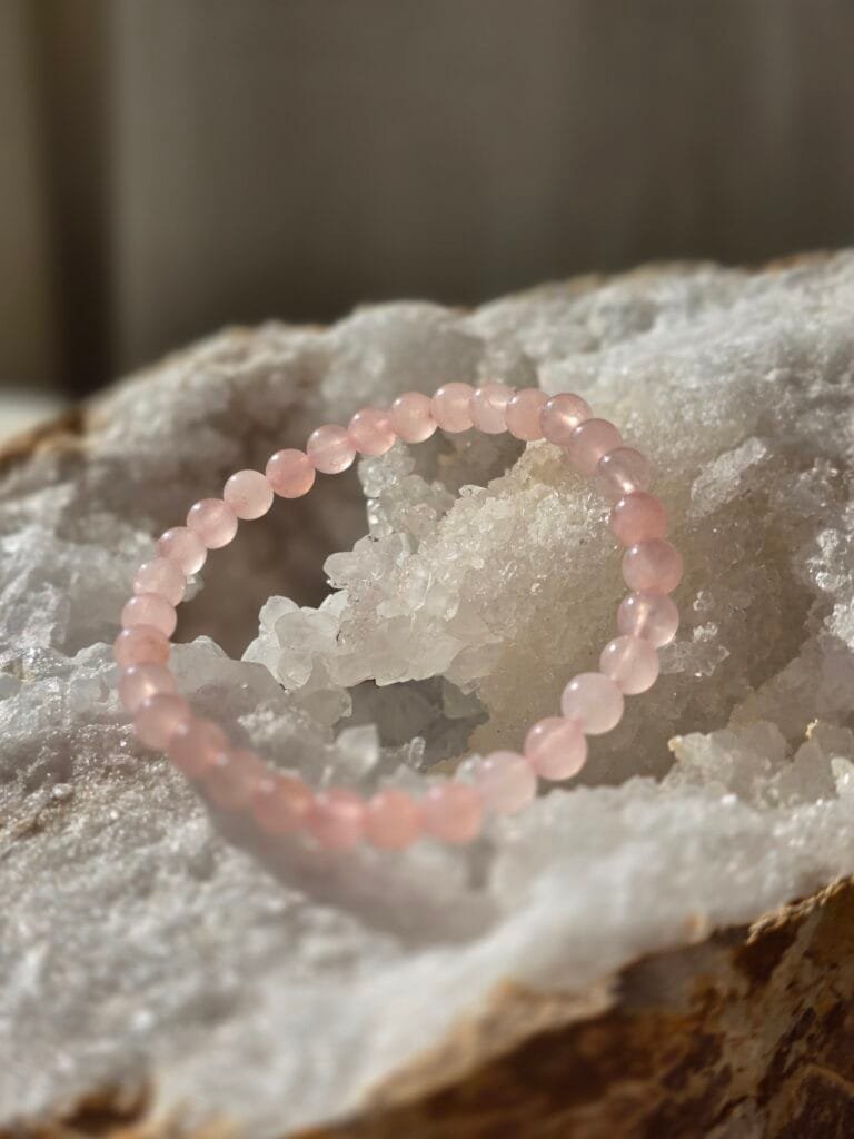 Bracelet en quartz rose naturel 6 mm posé sur une géode de quartz