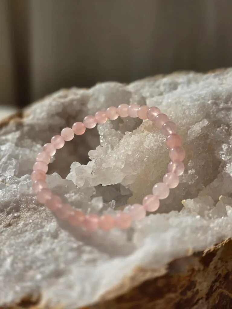 Bracelet en quartz rose naturel 6 mm posé sur une géode de quartz