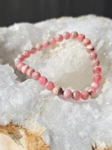 Bracelet en perles naturelles de Rhodochrosite 6 mm posé sur une géode de quartz