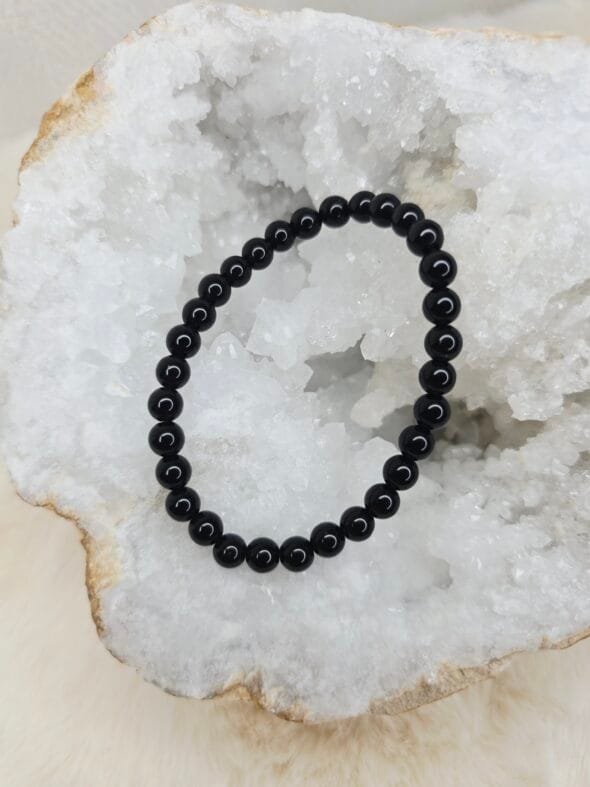 Pierre brute de tourmaline noire posée sur une géode de quartz blanc cristallin.