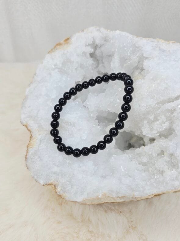 Pierre brute de tourmaline noire posée sur une géode de quartz blanc cristallin.
