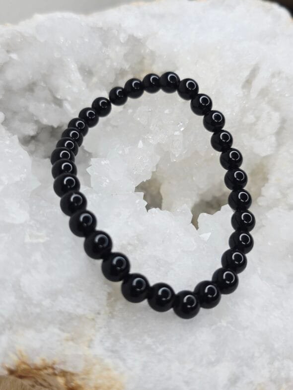 Pierre brute de tourmaline noire posée sur une géode de quartz blanc cristallin.