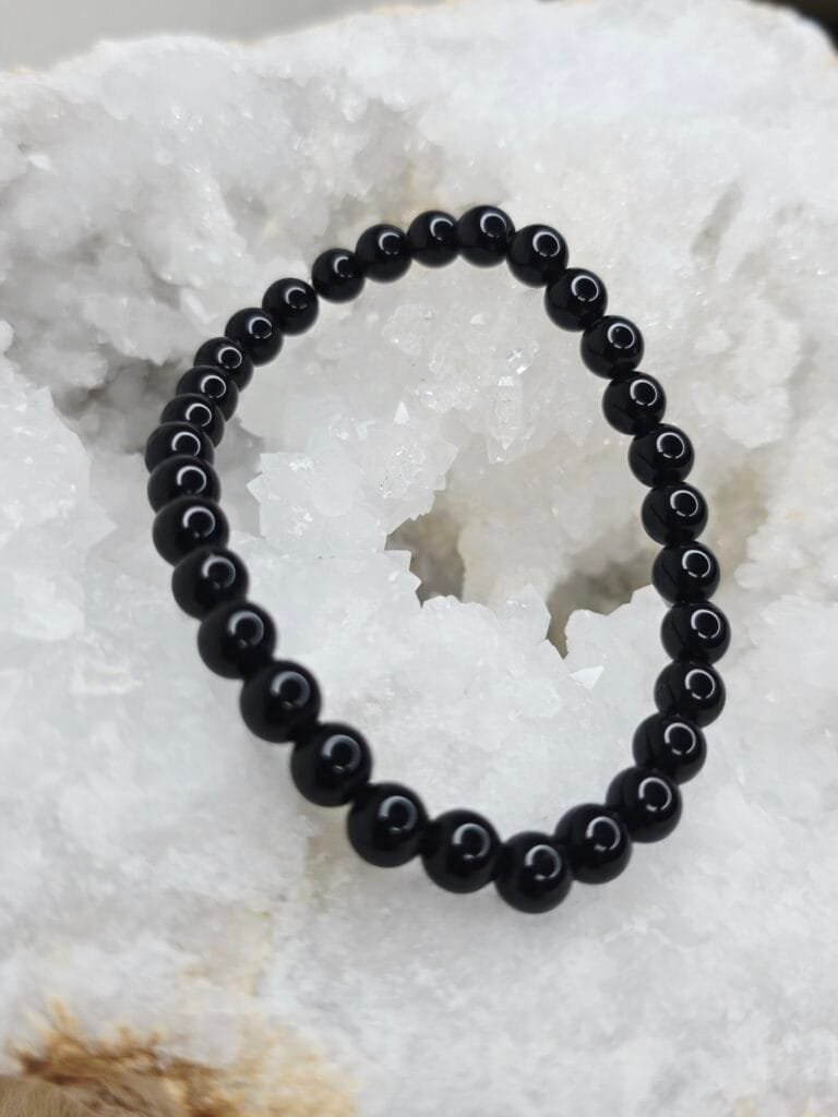 Pierre brute de tourmaline noire posée sur une géode de quartz blanc cristallin.