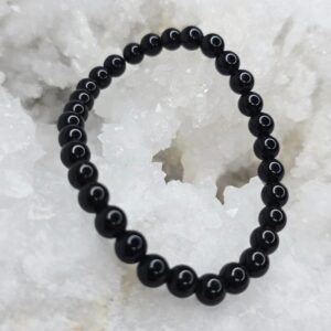 Pierre brute de tourmaline noire posée sur une géode de quartz blanc cristallin.