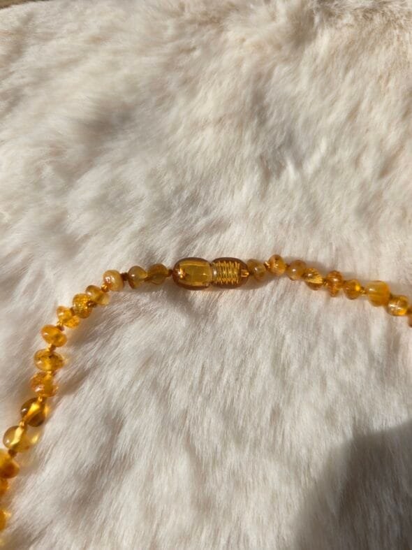 Collier bébé Ambre Miel AA sur fond neutre