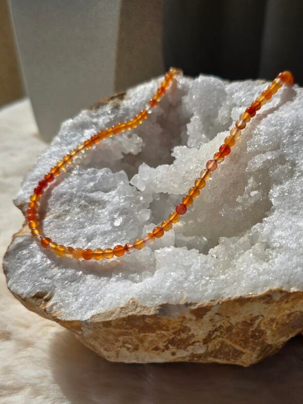 Collier en perles naturelles de cornaline 4 mm posé sur une géode, bijou artisanal et énergétique.