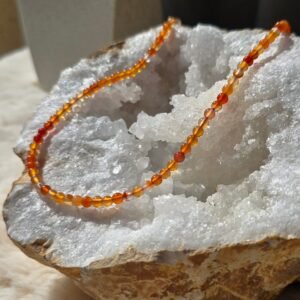 Collier en perles naturelles de cornaline 4 mm posé sur une géode, bijou artisanal et énergétique.