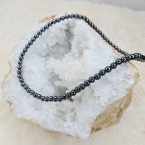 Collier en perles naturelles d’Hématite 6 mm posé sur une géode, bijou artisanal et énergétique.