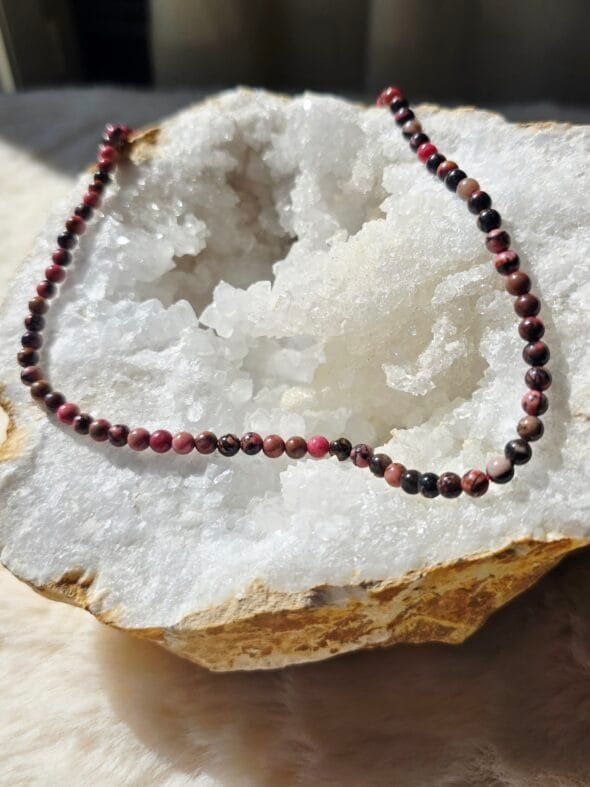 Collier en rhodonite naturelle 4 mm posé sur une géode