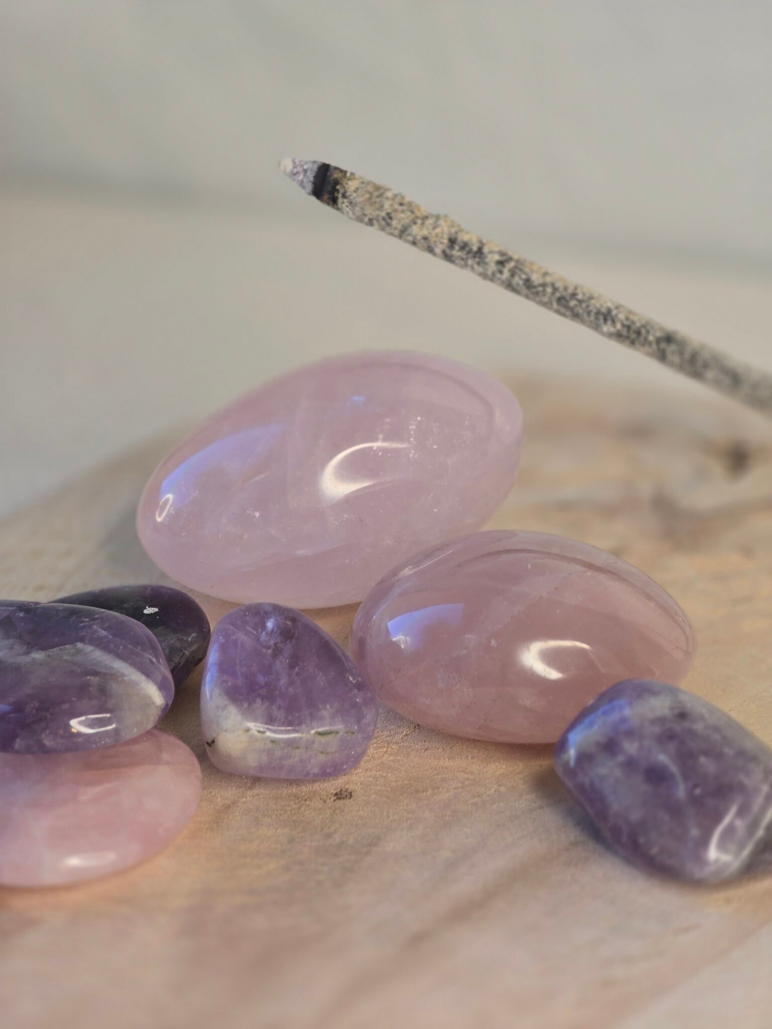 Main tenant un bâton d’encens de copal allumé avec quartz rose et améthyste