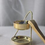 Encensoir avec résine de copal fumante et bâton de Palo Santo posé à côté, ambiance rituelle et purifiante