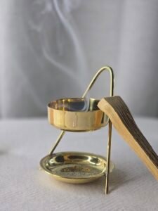 Encensoir avec résine de copal fumante et bâton de Palo Santo posé à côté, ambiance rituelle et purifiante