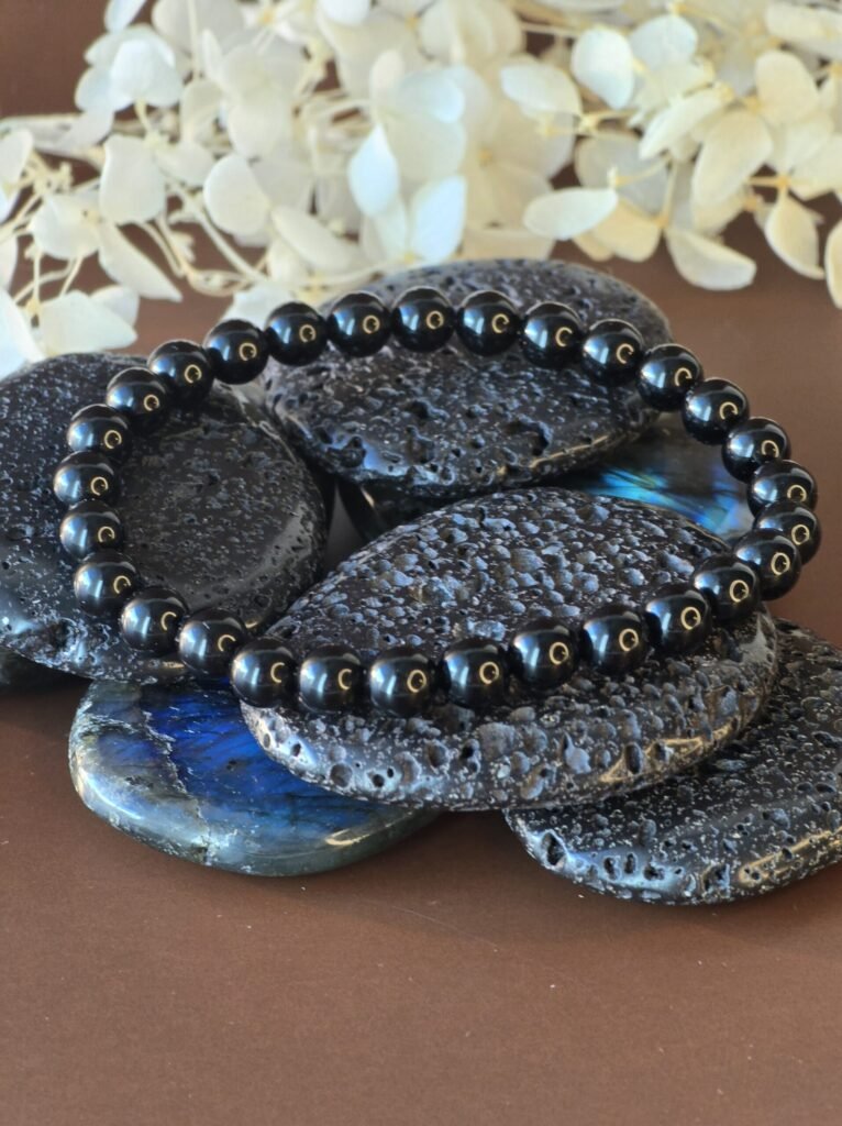 Bracelet tourmaline noire sur fond marron avec bougie en arrière-plan pour protection énergétique