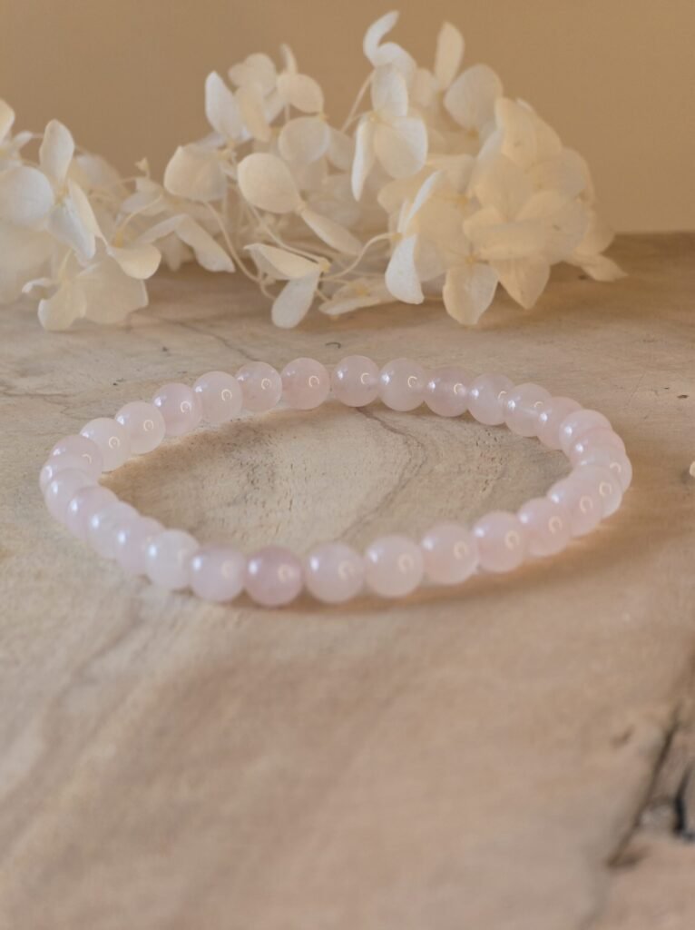 Bracelet en quartz rose naturel 6 mm posé sur une géode de quartz
