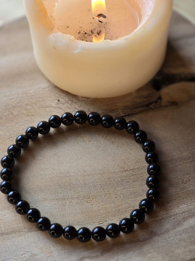 Bracelet tourmaline noire sur bois naturel avec bougie en arrière-plan pour protection énergétique