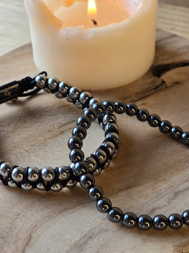 Bracelets hématite homme et femme sur bois avec bougie pour ancrage mental et concentration