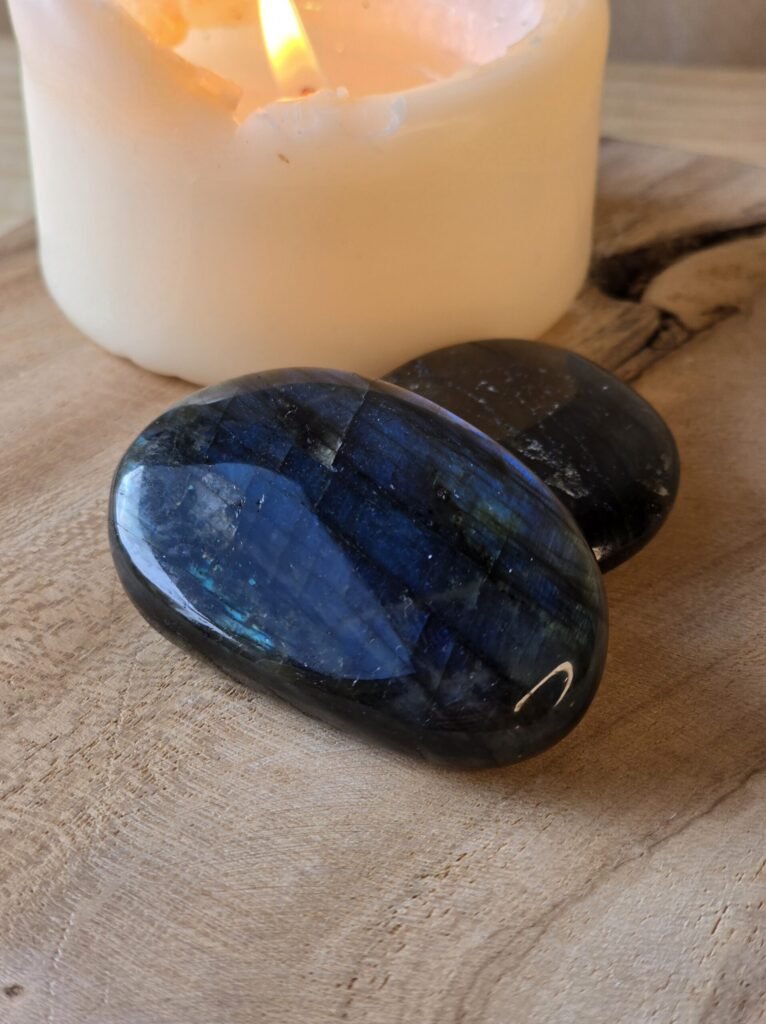Galets de labradorite sur bois clair avec bougie pour protection douce et équilibre émotionnel