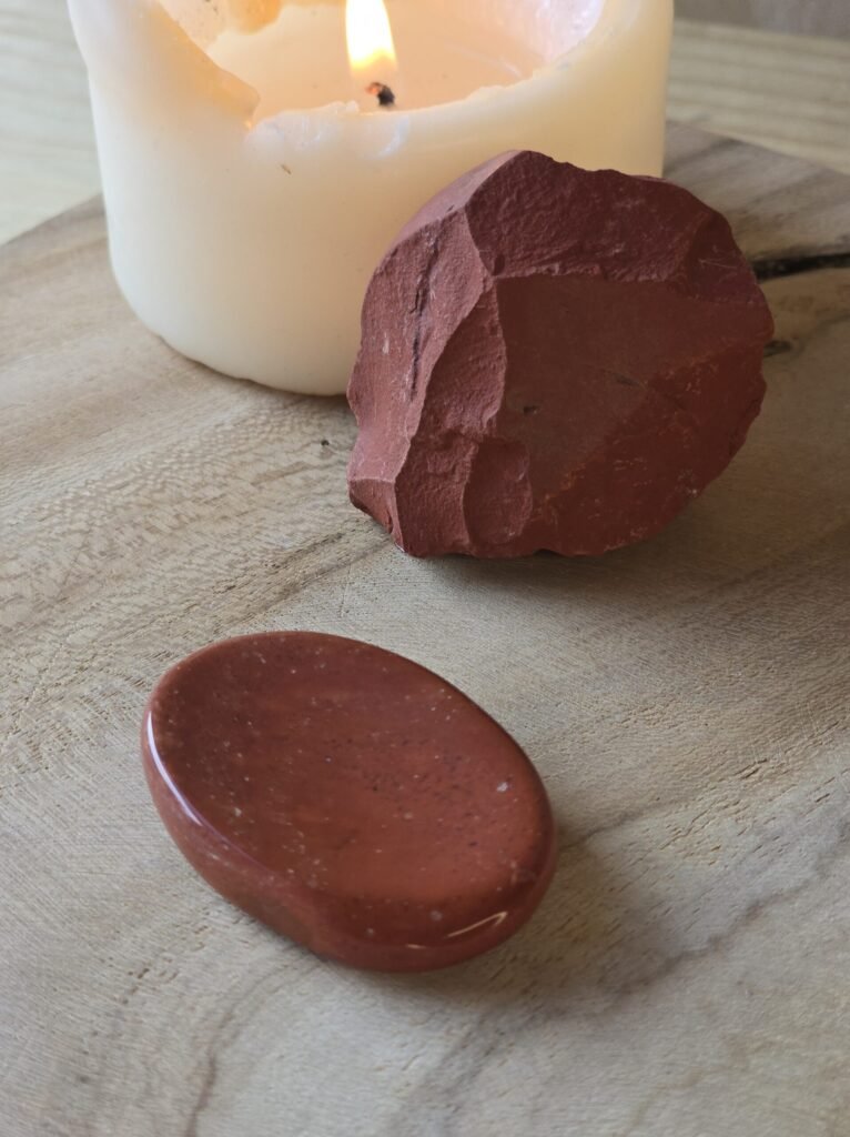 Pierre brute et pierre de souci en jaspe rouge sur bois naturel avec bougie pour stabilité et vitalité
