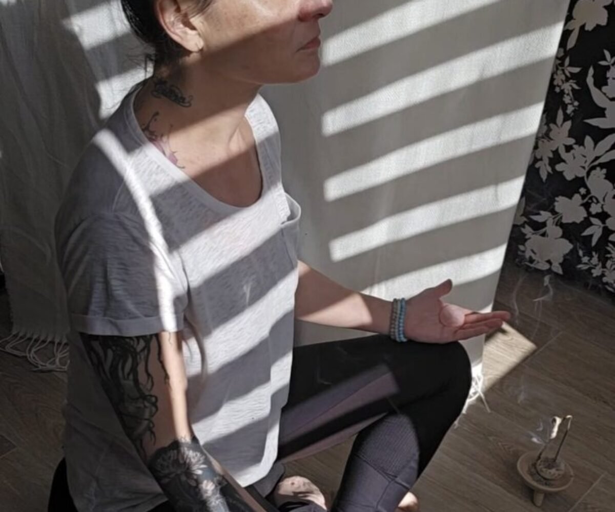 Femme en méditation tenant un cristal de lithothérapie, lumière naturelle douce, ambiance zen avec bois et lin