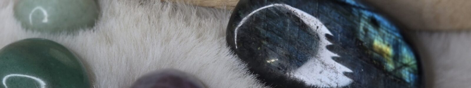 Quatre pierres naturelles posées sur un tapis poils crème : Labradorite gris bleuté, Quartz rose tendre, Améthyste violette et Aventurine verte. Vue en flat lay, ambiance douce et épurée.